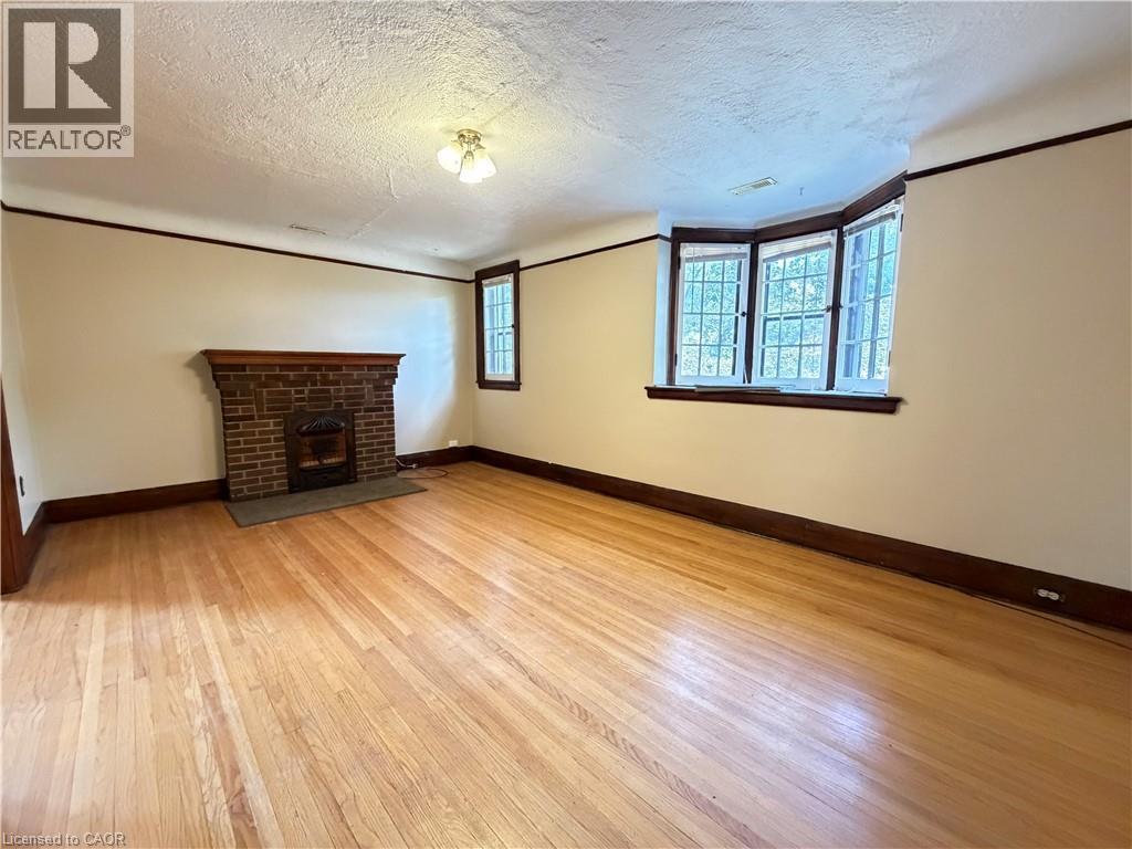 Hardwood flooring, brick-faced fireplace with wood mantel, bay window, and cased window - 507 Aberdeen Avenue, Hamilton, ON