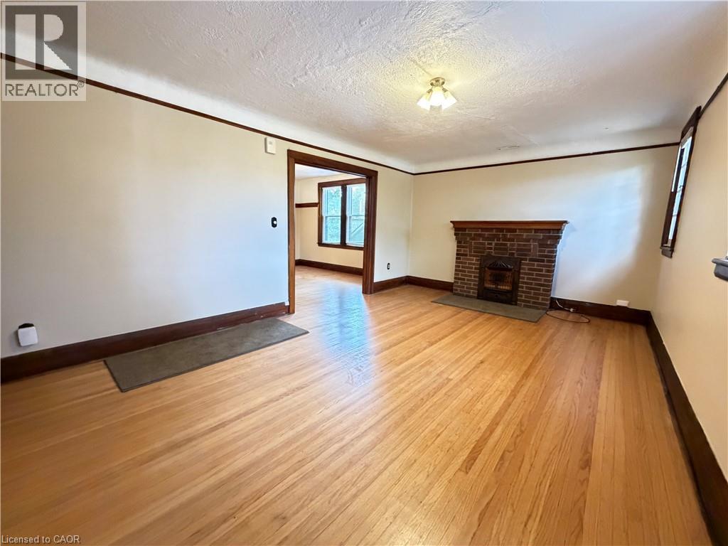 Wood-finish flooring, brick fireplace with mantel, ceiling-mounted light fixture, and wood trim detailing - 507 Aberdeen Avenue, Hamilton, ON