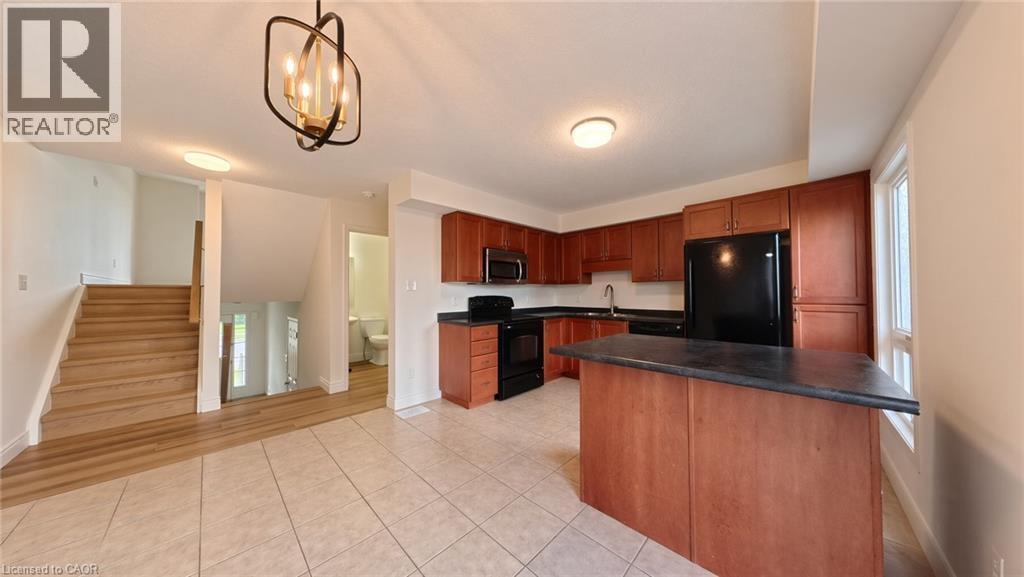 Kitchen with wood-finish cabinetry, black appliances, and a central island - 250 Parkvale Drive, Kitchener, ON