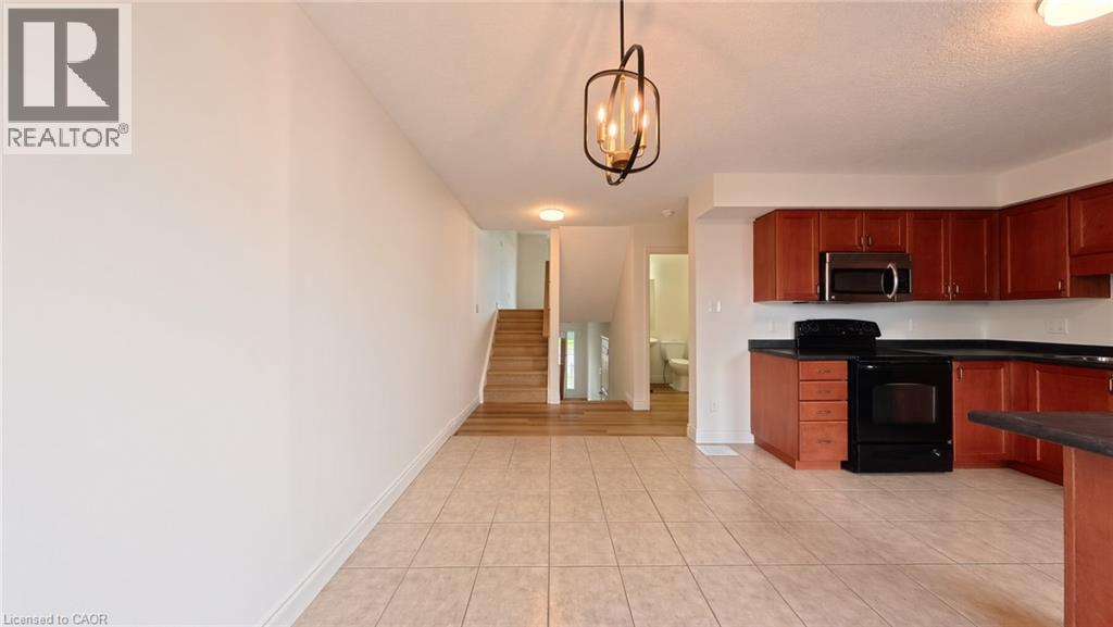 Kitchen featuring wood-finish cabinetry, black appliances, and dark countertops - 250 Parkvale Drive, Kitchener, ON