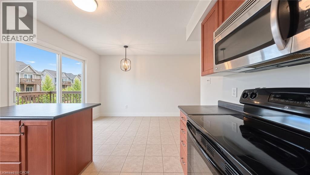 Kitchen featuring wood-finish cabinetry, stainless steel microwave, black electric range, and dark countertops - 250 Parkvale Drive, Kitchener, ON