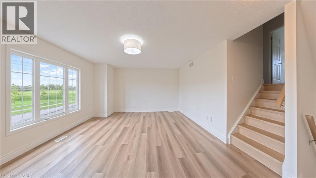 Spacious room with wood-finish flooring, a large multi-pane window, and a drum ceiling light fixture - 250 Parkvale Drive, Kitchener, ON
