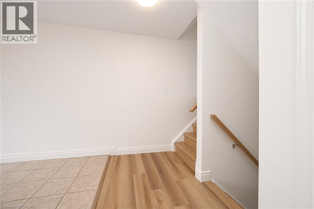 Wood-finish flooring, tiled entry, light wood handrails, and white painted walls - 250 Parkvale Drive, Kitchener, ON
