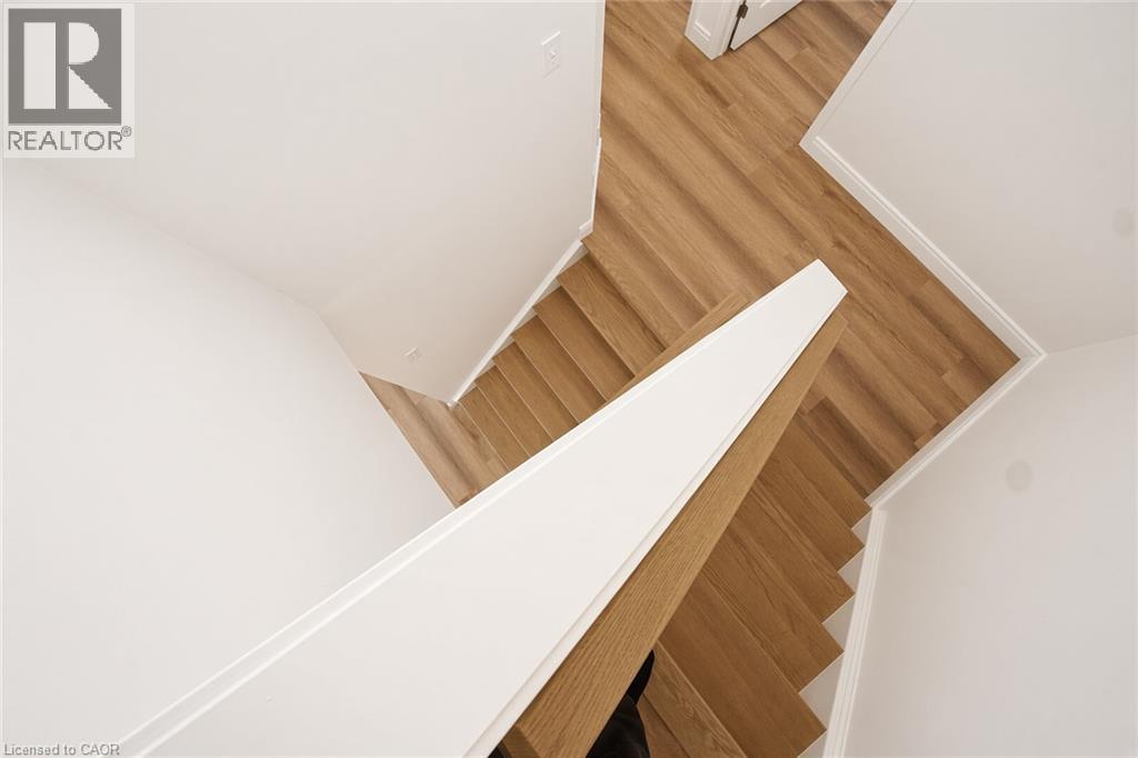 Wood-finish flooring with white trim and a contrasting white and wood-finish stair railing - 250 Parkvale Drive, Kitchener, ON