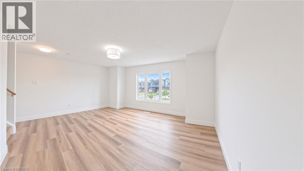 Spacious room featuring wood-finish flooring, white walls, and a large window - 250 Parkvale Drive, Kitchener, ON