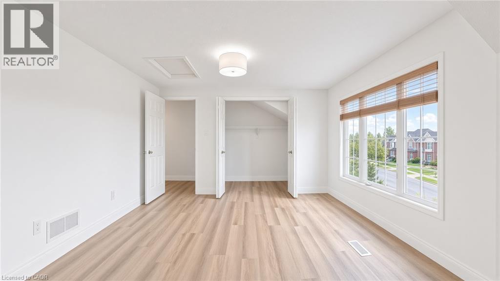 Expansive room featuring wood-finish flooring, a large multi-pane window, and a built-in closet - 250 Parkvale Drive, Kitchener, ON