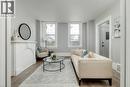 Bright living space featuring wood-finish flooring, a decorative fireplace mantel, and two large windows - 125 Cathcart Street, Hamilton, ON 