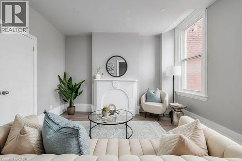Recessed lighting, wood-finish flooring, white door with silver hardware, white baseboards, and a decorative fireplace - 125 Cathcart Street, Hamilton, ON 