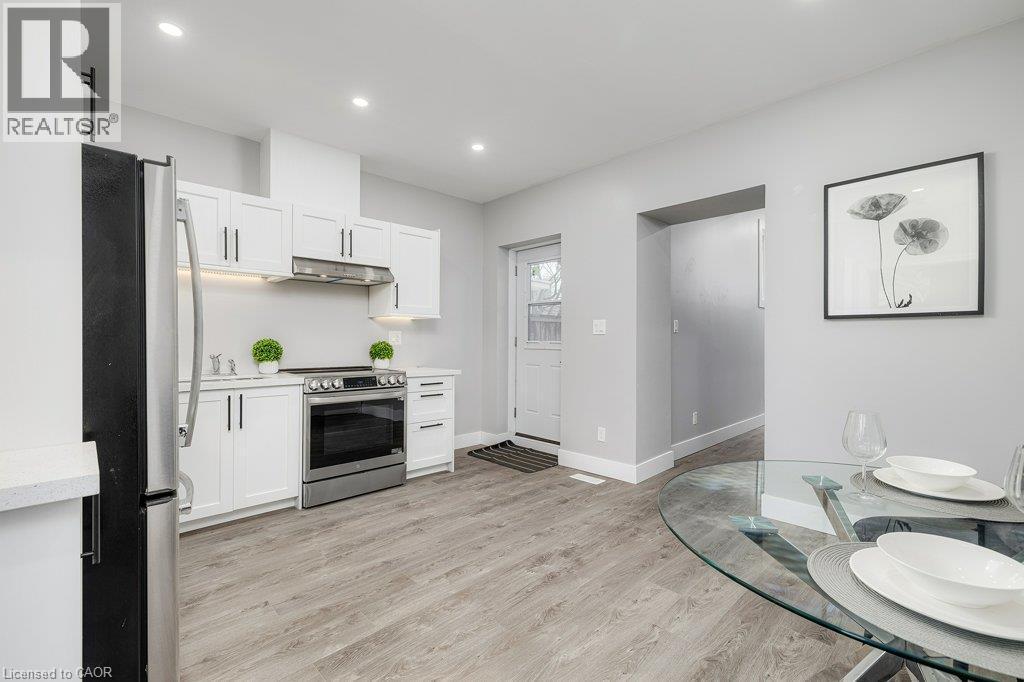 Modern kitchen featuring white cabinetry, stainless steel appliances, wood-finish flooring, and recessed lighting - 125 Cathcart Street, Hamilton, ON