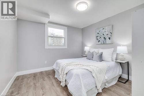 Neutral wall color, wood-finish flooring, white window trim, contemporary ceiling light fixture, and white baseboards - 125 Cathcart Street, Hamilton, ON 