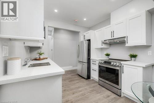Kitchen featuring white shaker-style cabinetry, stainless steel appliances, light-toned countertops, and wood-finish flooring - 125 Cathcart Street, Hamilton, ON 