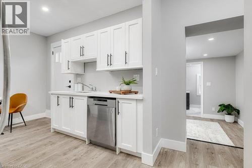 White shaker cabinetry with matte black hardware, stainless steel dishwasher, undermount sink, and wood-finish flooring - 125 Cathcart Street, Hamilton, ON 