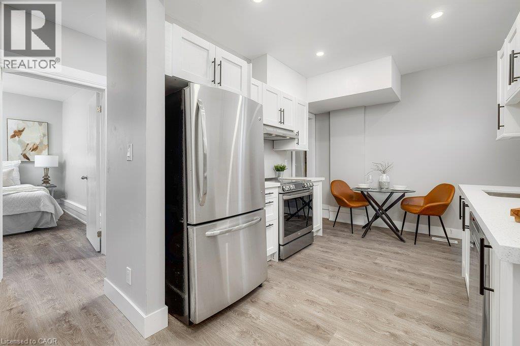 Modern kitchen featuring stainless steel appliances, white cabinetry with black hardware, light-toned wood-finish flooring, and recessed lighting - 125 Cathcart Street, Hamilton, ON