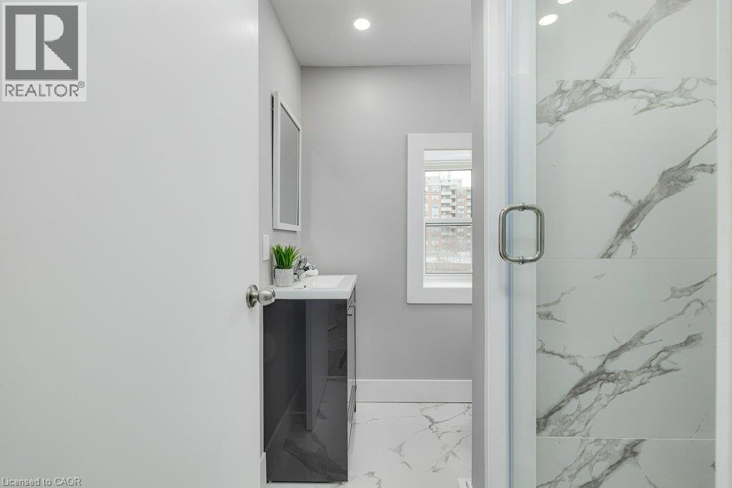 Shower with clear glass enclosure, white and grey veined wall tile, and recessed lighting - 125 Cathcart Street, Hamilton, ON