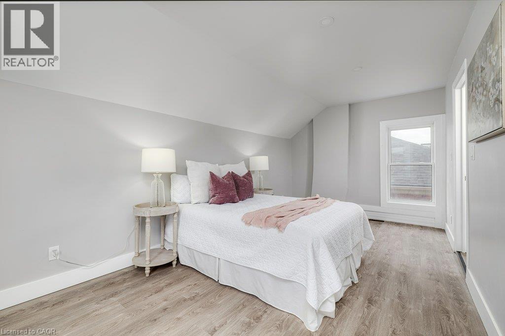 Sloped ceiling architecture, recessed lighting, wood-finish flooring, white trim, and a white framed window - 125 Cathcart Street, Hamilton, ON