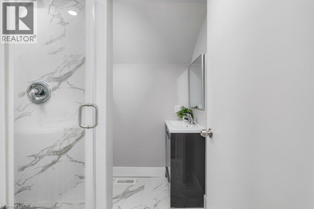 Glass-enclosed shower with chrome fixtures, white and gray veined tile, and recessed lighting - 125 Cathcart Street, Hamilton, ON