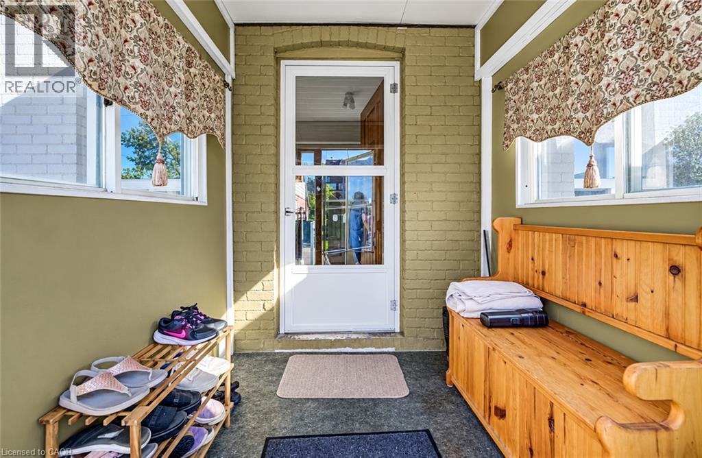Enclosed entryway featuring painted brick walls, multiple windows, and a glass-paneled entry door - 3 Craigmiller Avenue, Hamilton, ON