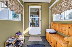 Enclosed entryway featuring painted brick walls, multiple windows, and a glass-paneled entry door -