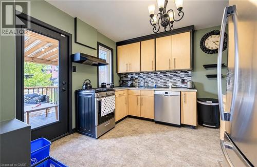 Kitchen featuring light wood-finish cabinetry, stainless steel appliances, mosaic tile backsplash, and direct access to an outdoor deck - 3 Craigmiller Avenue, Hamilton, ON 