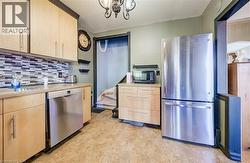 Kitchen featuring wood-finish cabinetry, stainless steel dishwasher, and stainless steel refrigerator -