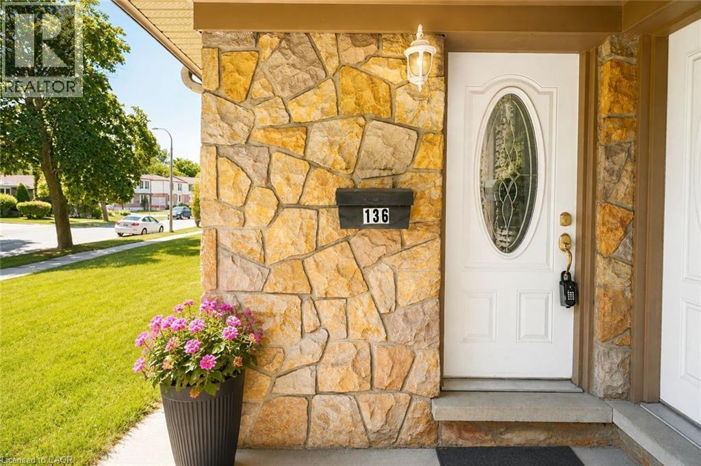 Stone veneer exterior with a white front door featuring an oval-shaped decorative glass insert, complemented by an overhead exterior light fixture - 136 Jansen Avenue, Kitchener, ON