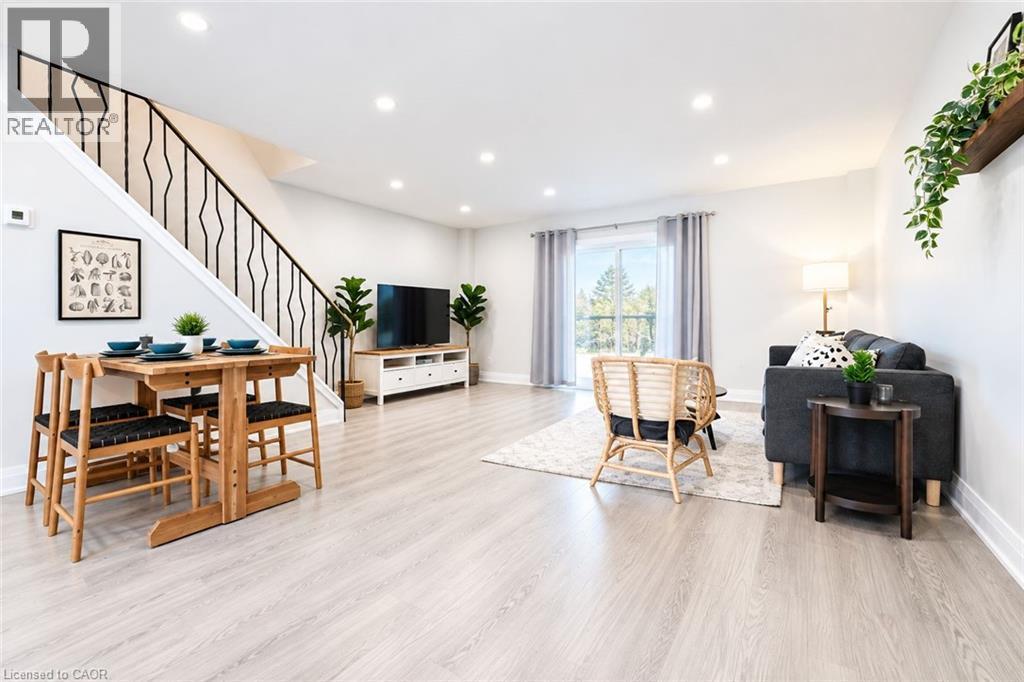 Open-concept living area featuring light wood-finish flooring, recessed lighting, and a contemporary staircase with a black metal railing - 136 Jansen Avenue, Kitchener, ON