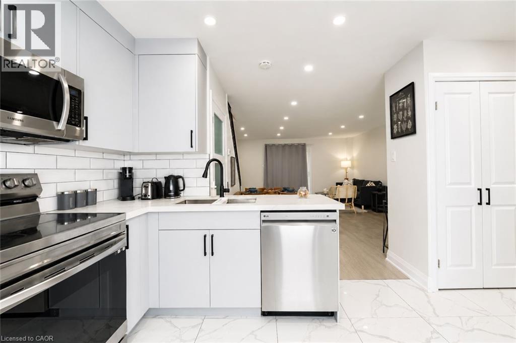 White shaker-style cabinetry with matte black hardware, stainless steel appliances, white subway tile backsplash, white countertop, and recessed lighting - 136 Jansen Avenue, Kitchener, ON