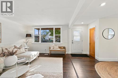 Wood-finish flooring throughout, white paneled accent wall, recessed lighting, and a white entry door with frosted glass panels - 284 East 21St Street, Hamilton, ON 
