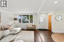 Wood-finish flooring throughout, white paneled accent wall, recessed lighting, and a white entry door with frosted glass panels - 284 East 21St Street, Hamilton, ON 