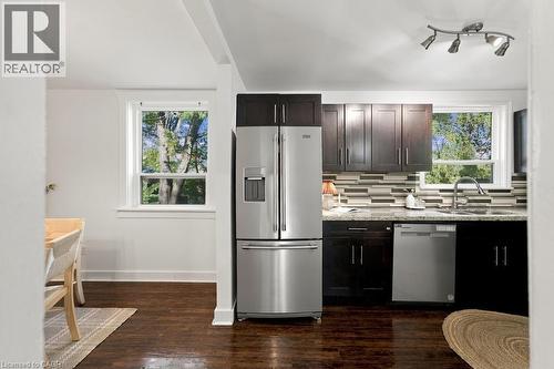 Kitchen with stainless steel appliances, dark wood-finish cabinetry, granite-style countertops, and mosaic tile backsplash - 284 East 21St Street, Hamilton, ON 