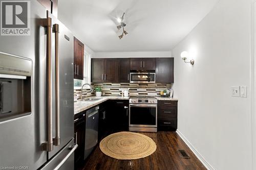 Stainless steel appliances, dark wood cabinetry, granite countertops, and a tiled backsplash - 284 East 21St Street, Hamilton, ON 
