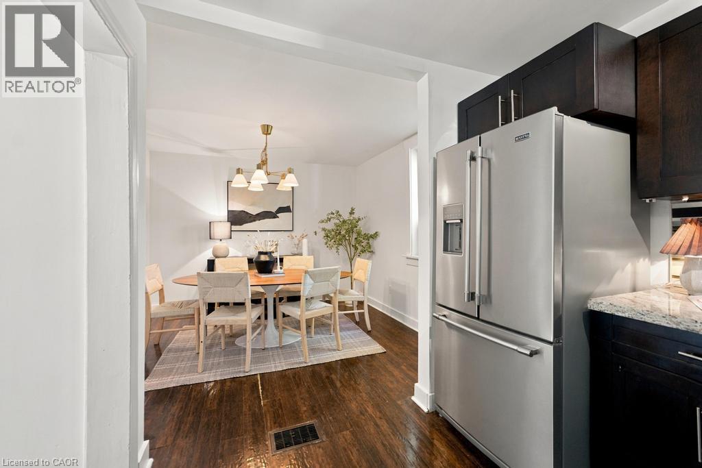 Stainless steel refrigerator, dark wood-finish cabinetry, granite countertop, wood-finish flooring, and recessed lighting - 284 East 21St Street, Hamilton, ON