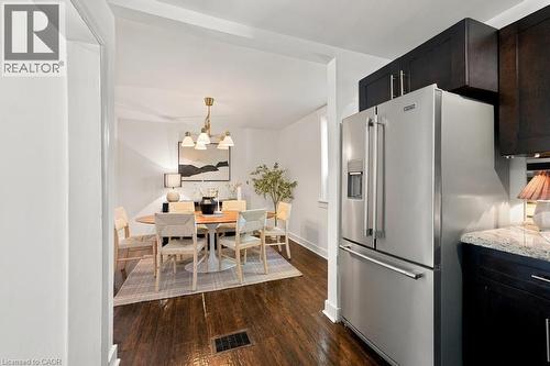 Stainless steel refrigerator, dark wood-finish cabinetry, granite countertop, wood-finish flooring, and recessed lighting - 284 East 21St Street, Hamilton, ON 