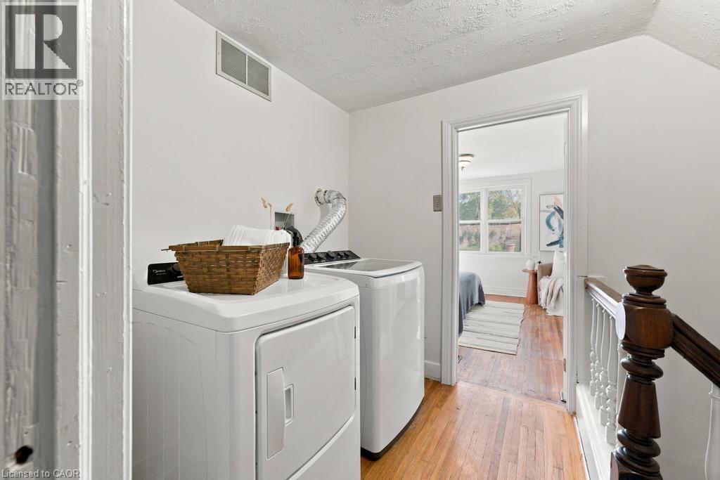 Hallway featuring wood-finish flooring, white walls, and a wood banister with white spindles - 284 East 21St Street, Hamilton, ON