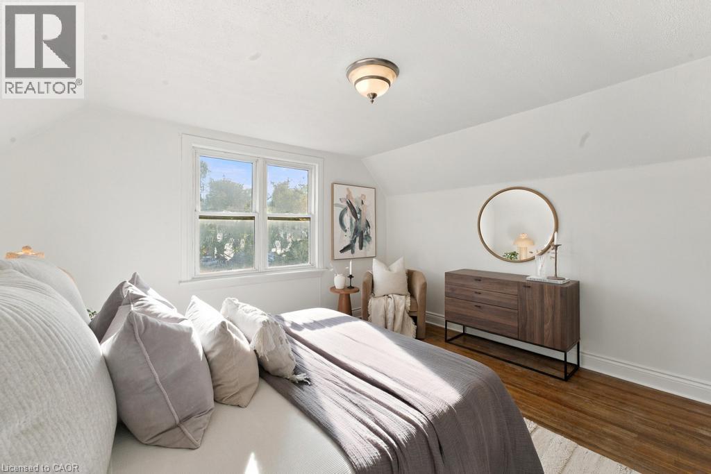 Recessed window with white trim, wood-finish flooring, white walls, angled ceiling, and a flush mount light fixture - 284 East 21St Street, Hamilton, ON