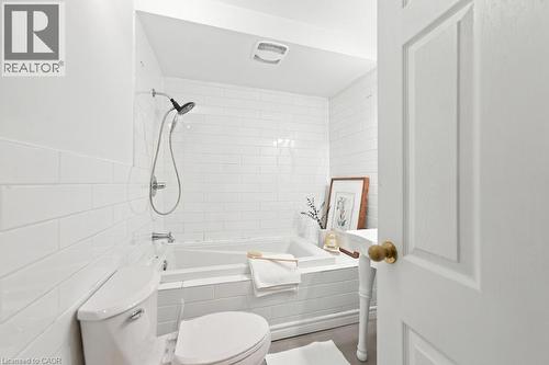 White subway tile bath surround, ceramic toilet, and a white vanity with a rectangular basin - 284 East 21St Street, Hamilton, ON 