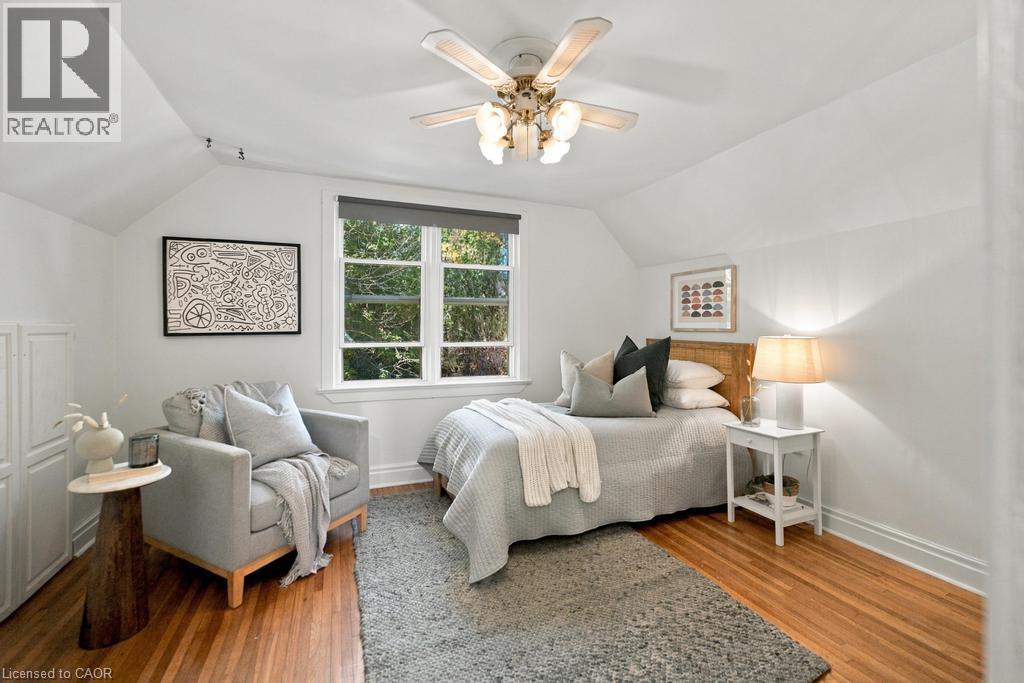 Wood-finish flooring with a ceiling fan light fixture, multi-pane window, and sloped ceiling - 284 East 21St Street, Hamilton, ON