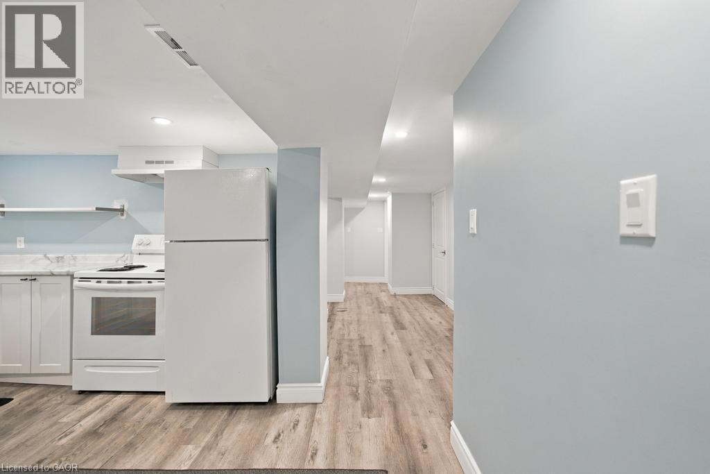 White appliances, light wood-finish flooring, recessed lighting, white cabinetry, and light blue walls - 284 East 21St Street, Hamilton, ON