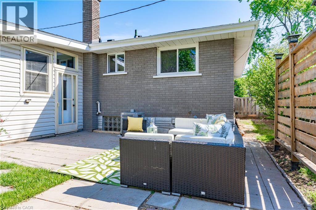 Patio area featuring concrete pavers, a wooden privacy fence, and brick exterior - 388 Appleby Line, Burlington, ON