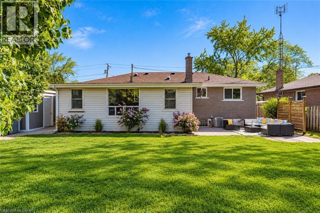 Expansive rear lawn, paved patio area, white siding, brick exterior, and a detached storage shed - 388 Appleby Line, Burlington, ON
