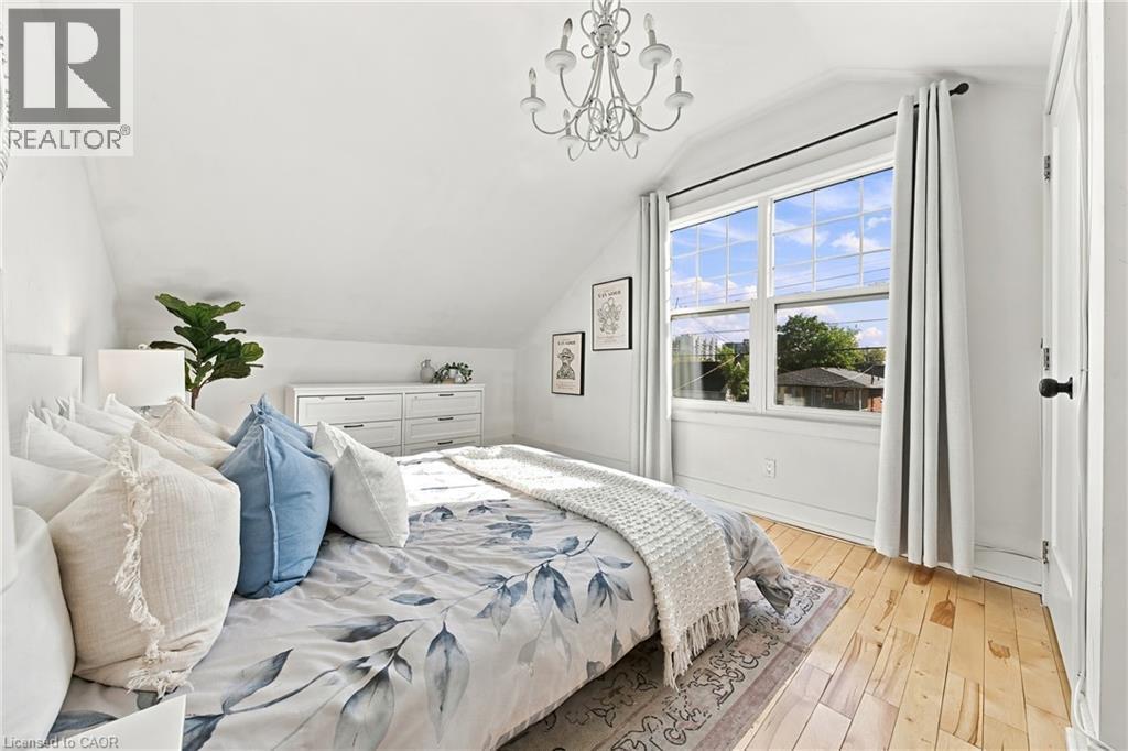 Vaulted ceiling with a chandelier, wood-finish flooring, white double-pane window, and white trim - 1231 Dunsmure Road, Hamilton, ON
