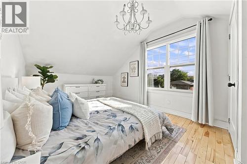 Vaulted ceiling with a chandelier, wood-finish flooring, white double-pane window, and white trim - 1231 Dunsmure Road, Hamilton, ON 