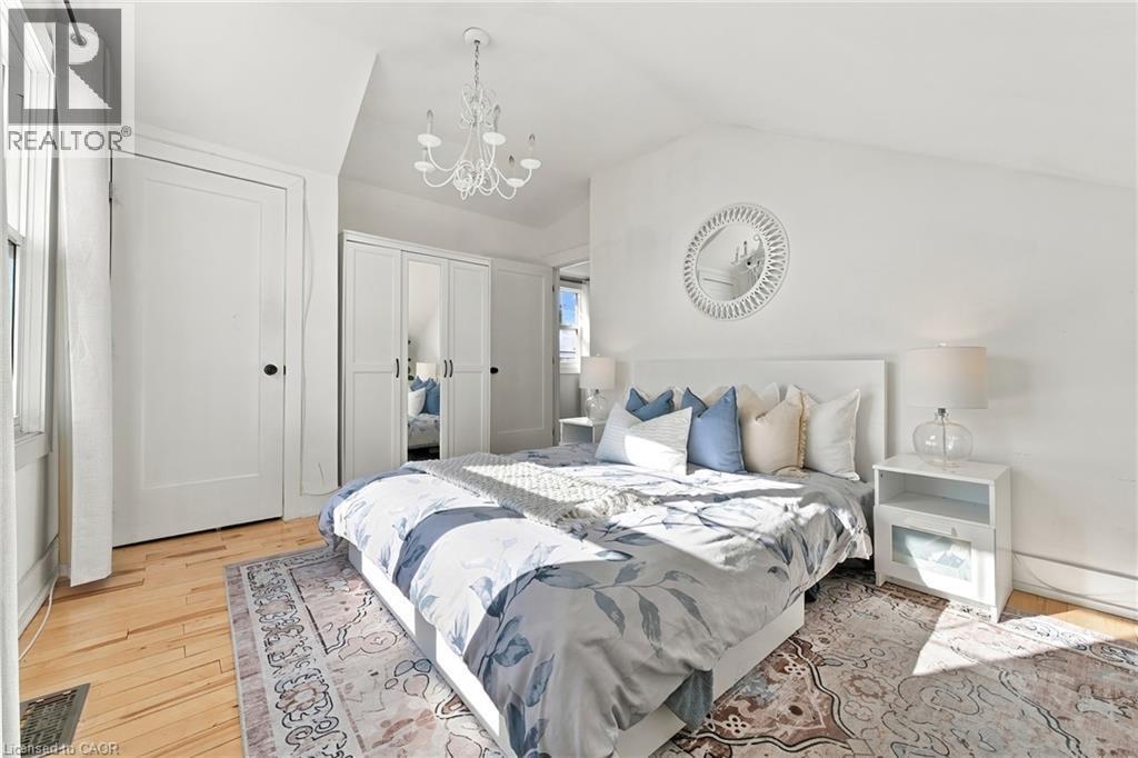 Hardwood flooring, prominent window, built-in wardrobe with mirrored panels, chandelier, and a decorative wall mirror - 1231 Dunsmure Road, Hamilton, ON