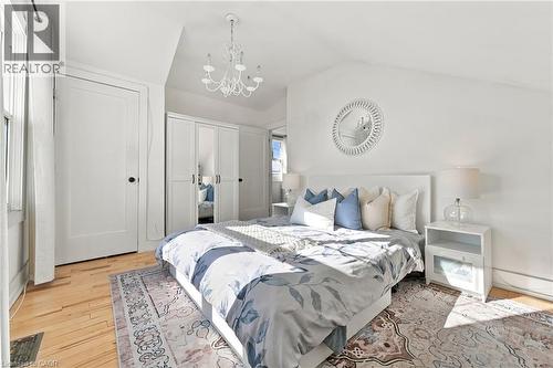 Hardwood flooring, prominent window, built-in wardrobe with mirrored panels, chandelier, and a decorative wall mirror - 1231 Dunsmure Road, Hamilton, ON 