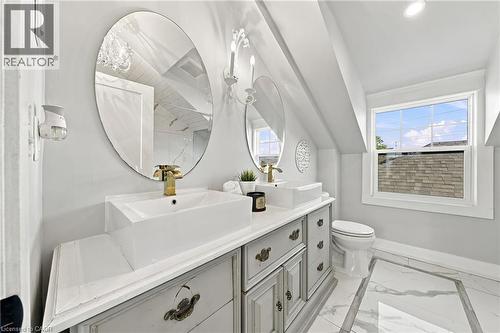Dual vessel sinks with gold-tone hardware, oval mirrors, and a multi-pane window - 1231 Dunsmure Road, Hamilton, ON 