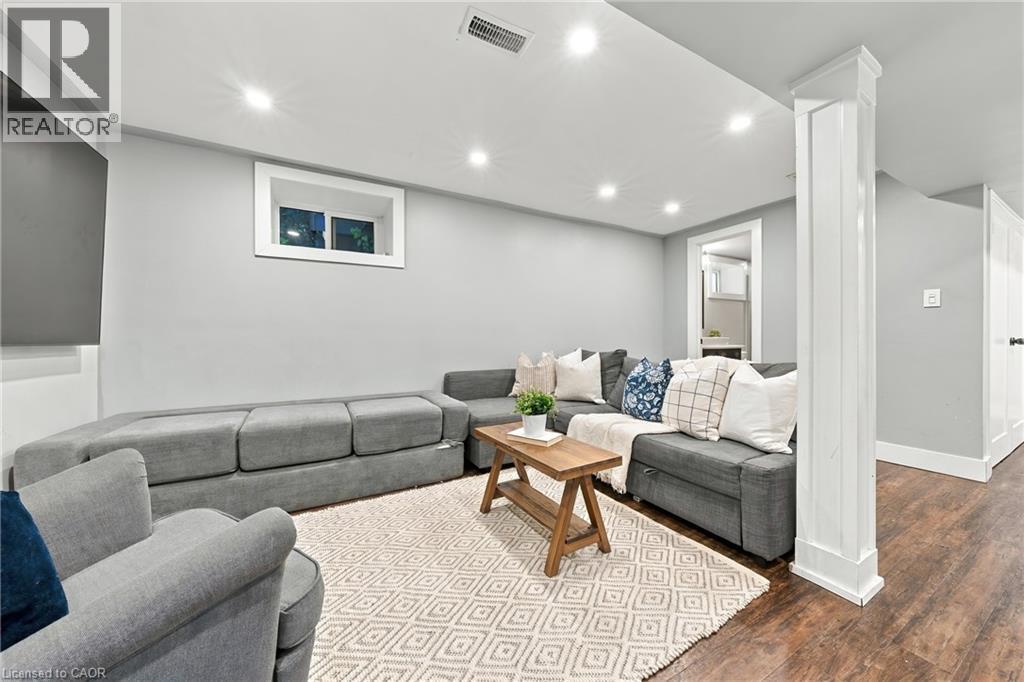 Recessed lighting illuminates the living space, featuring wood-finish flooring and a white trimmed window - 1231 Dunsmure Road, Hamilton, ON