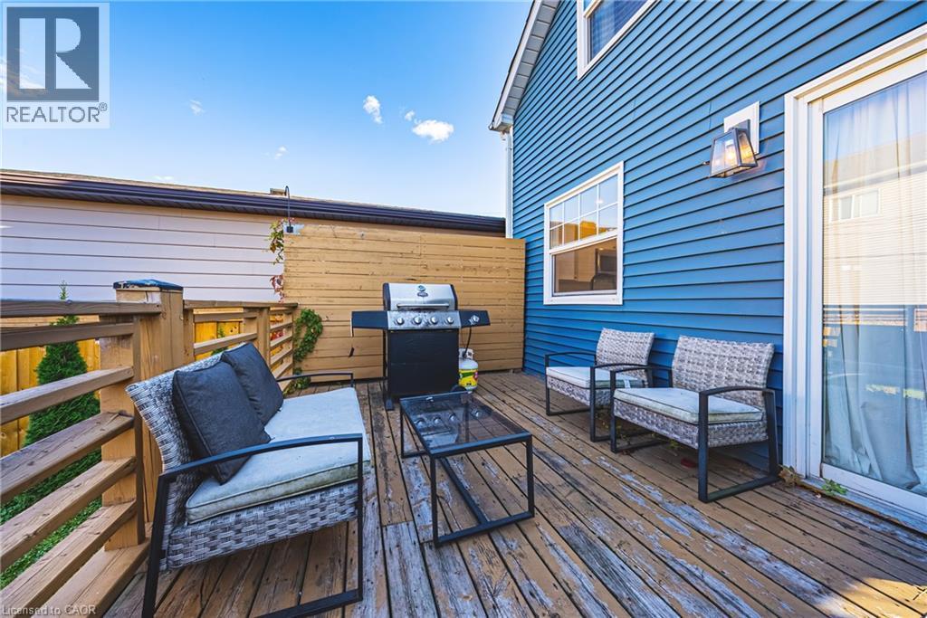 Wood deck surface with wood railings, sliding glass door entry, and exterior wall lighting - 1231 Dunsmure Road, Hamilton, ON