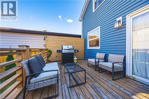 Wood deck surface with wood railings, sliding glass door entry, and exterior wall lighting - 1231 Dunsmure Road, Hamilton, ON 