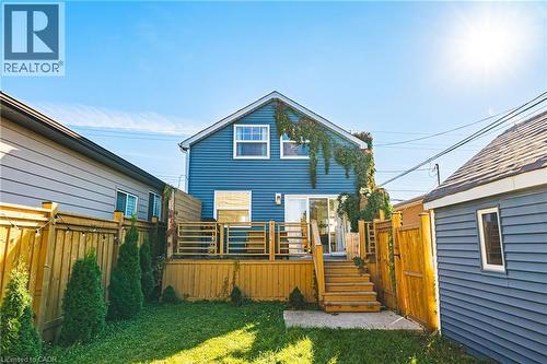 Rear exterior with blue siding, wood deck, sliding glass door, and a manicured lawn - 1231 Dunsmure Road, Hamilton, ON 