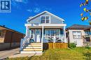 Blue siding exterior, white trim accents, prominent front porch with white railing, wood stairs, and a front yard with natural grass - 1231 Dunsmure Road, Hamilton, ON 